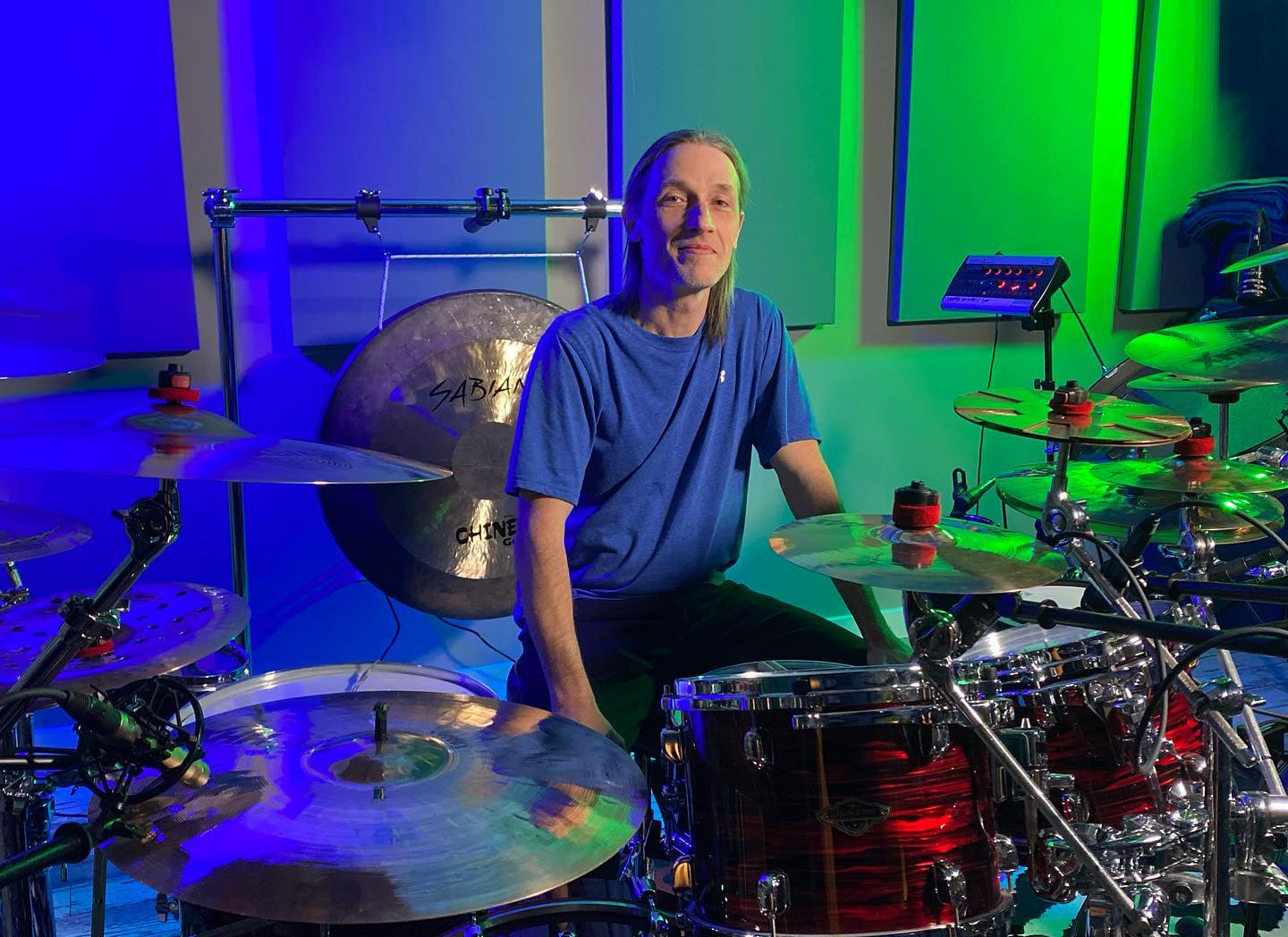 Person sitting behind a drum set with a colorful background